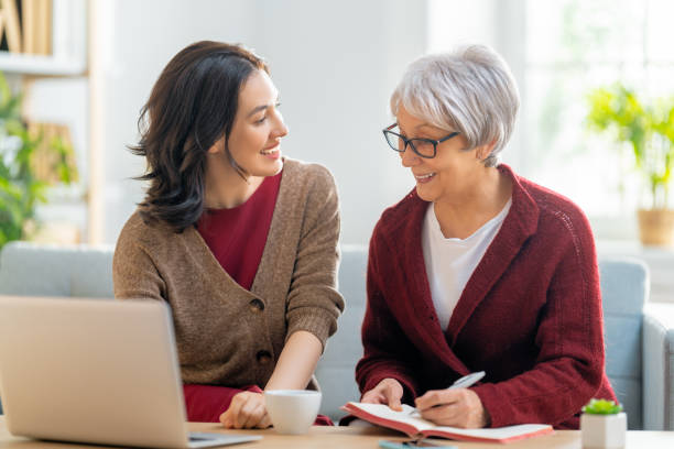 Two women smiling while using a laptop